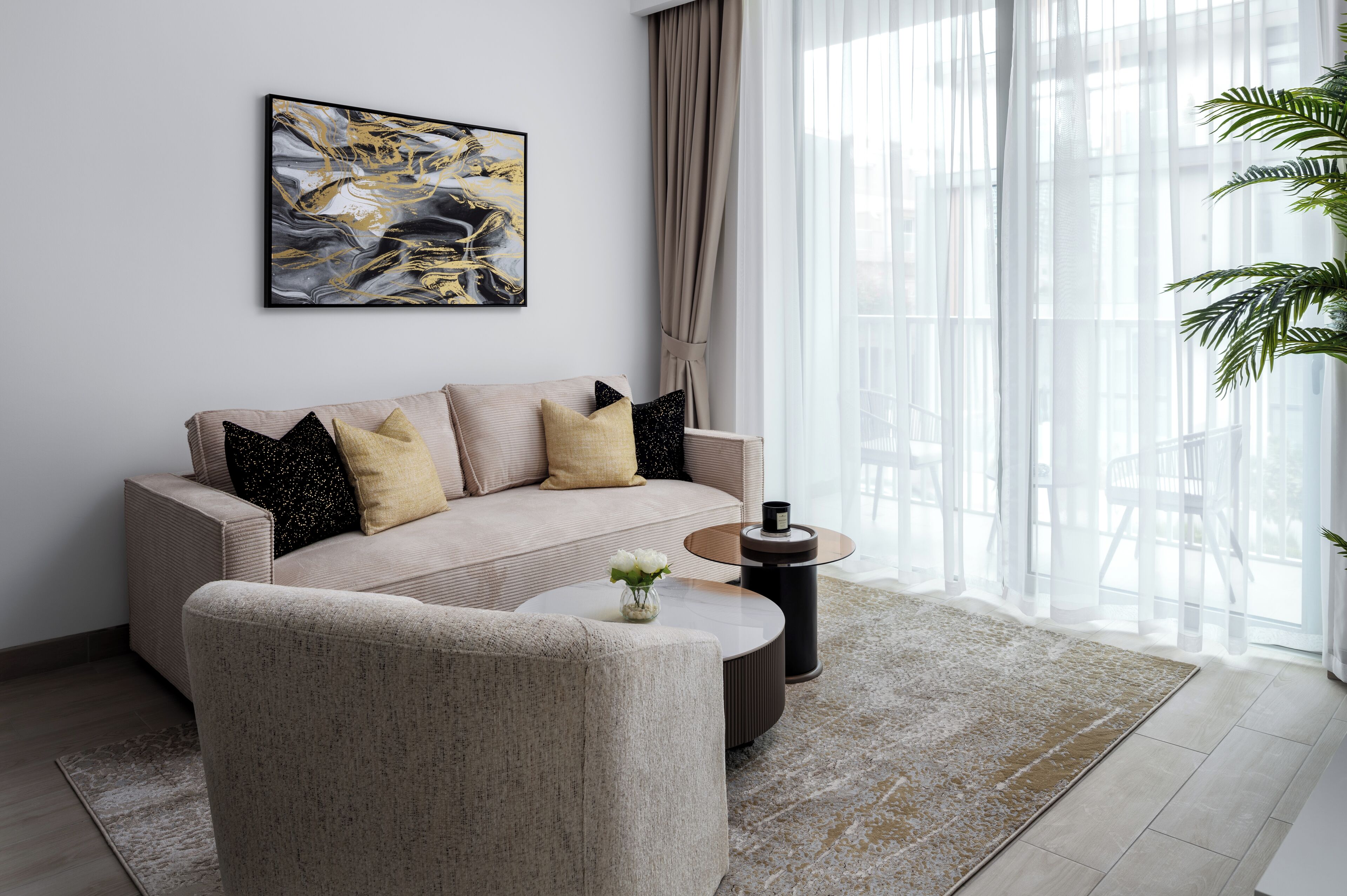 A modern living room with a beige sofa, a round coffee table, and a large abstract painting on the wall.
