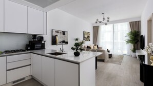 Une cuisine moderne avec des meubles blancs, un îlot central et un coin repas comprenant un canapé et une table basse.
