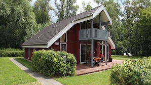 Ein rotes Haus mit geneigtem Dach und einem Balkon.