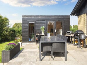 Relax on the patio with a grill and barbecue, surrounded by a grassy lawn and a wooden fence.