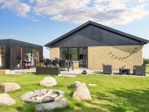 A modern building with a brick exterior and a black roof, featuring outdoor seating and a fire pit. - Tranquil Haven by Saksild - By Traum Ferienwohnungen (Odder)