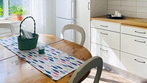 Una cocina con armarios blancos, encimera de madera y ventana con vistas a zonas verdes.