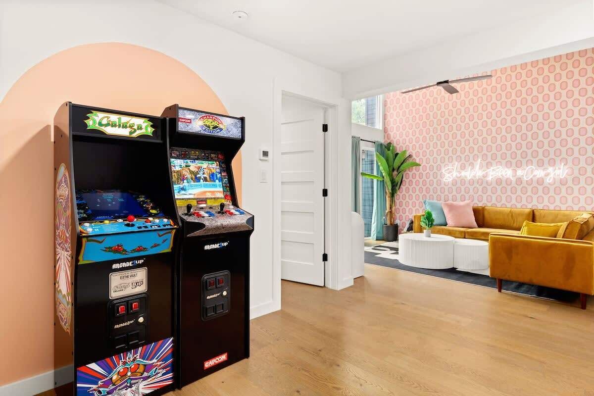 Två arkadspel, en vit dörr, en gul soffa och en vägg med mönster.