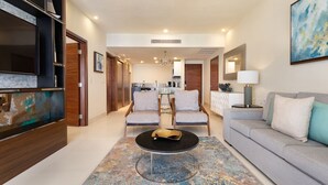 A modern living room with a sofa, two armchairs, a coffee table, and a TV on a wooden cabinet. - Amazing 1 bedroom condo, ocean view with AC in San José del Cabo (San José del Cabo)