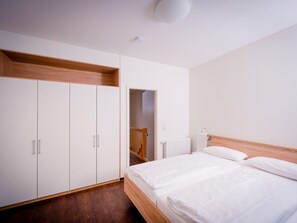 Un dormitorio con cama, armario blanco y techo de madera.