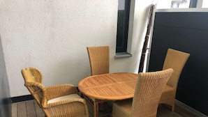 A small outdoor seating area with a round wooden table and four wicker chairs. - Appartementhaus Calmsailing, Borgerende (Boergerende-Rethwisch)