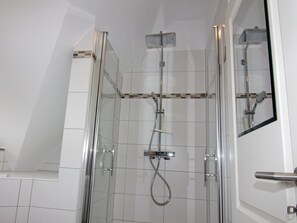 Eine separate Duschkabine mit Handbrause, fest installierter Duscharmatur und flexiblem Duschschlauch.