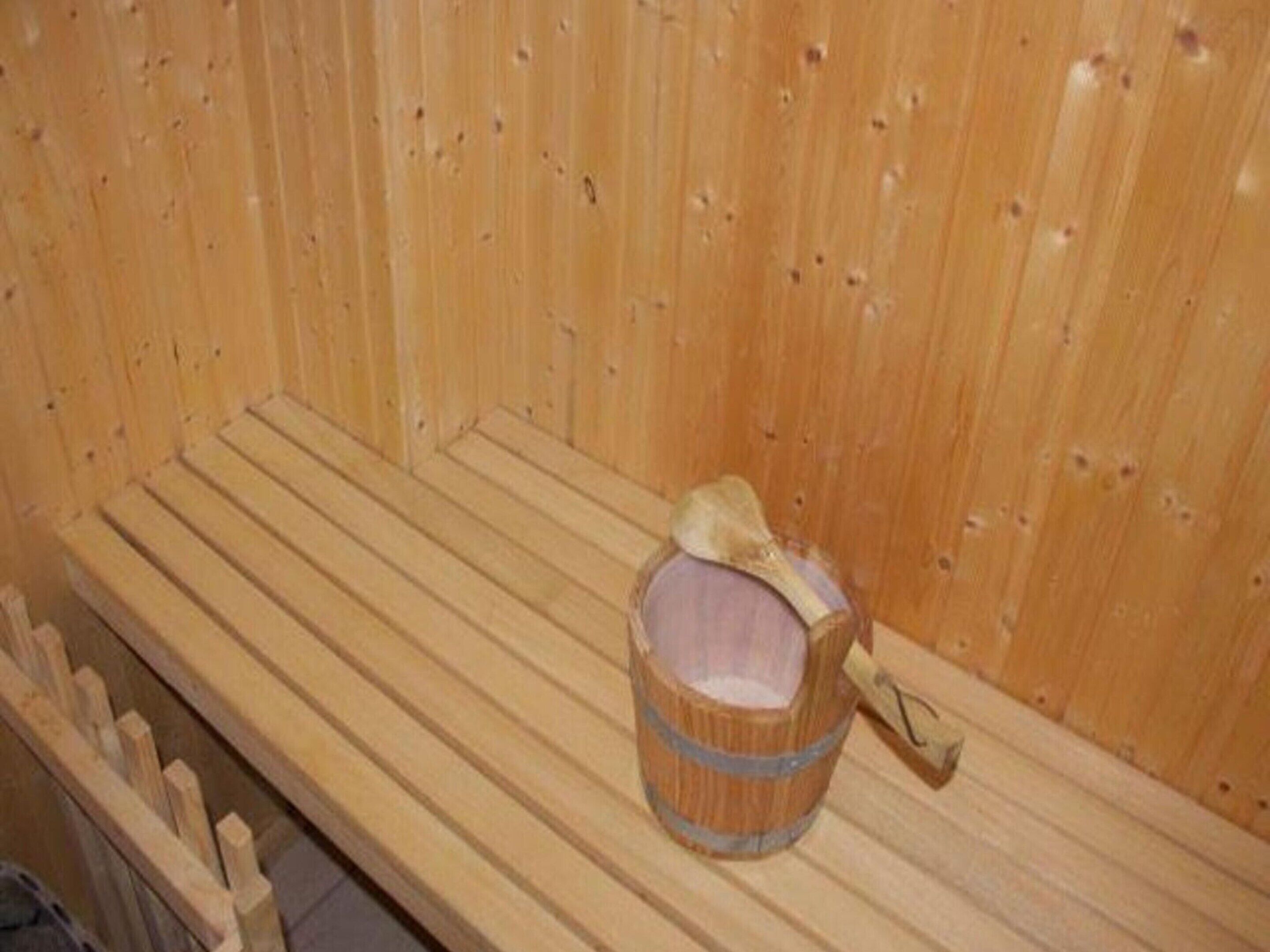 A wooden sauna bench with a wooden bucket placed on it.