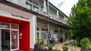 A hotel entrance with a red awning, outdoor seating, and potted plants. - Apartment fur den Perfekten Urlaub (Mirow)