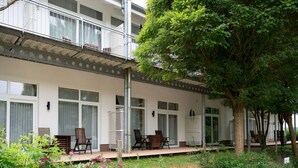 A two-story building with a balcony, outdoor seating, and a garden with flowers. - Apartment fur den Perfekten Urlaub (Mirow)