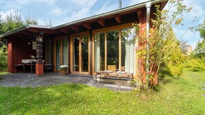 Una casa moderna con un portico coperto, ampie finestre e un giardino.