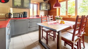 Una cucina moderna con soffitto in legno, un tavolo da pranzo con sedie e una finestra vista verde.
