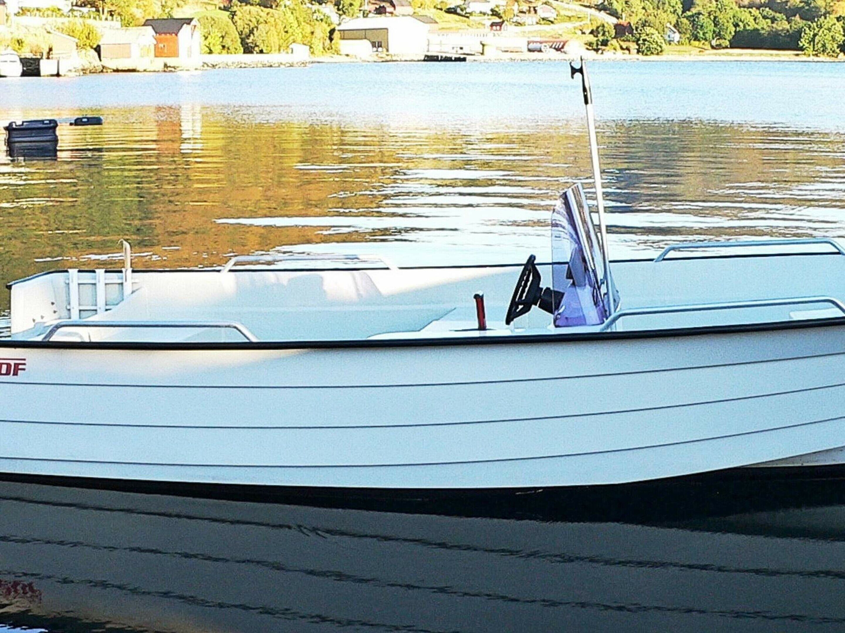 A boat docked at a marina with a clear view of the water and a distant shoreline.