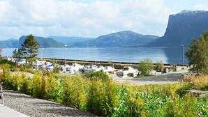 A marina with boats docked, a parking area, and a mountainous backdrop. - 5 Star Holiday Home in Sorbovag (Hyllestad)