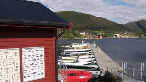 A red building with marine life illustrations, a dock with boats, and a mountainous landscape in the background. - 5 Star Holiday Home in Sorbovag (Hyllestad)