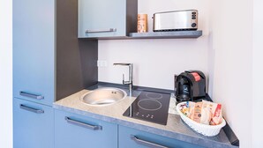 A modern kitchenette with a built-in stove, a sink, and a coffee maker. - Apartment Bad Camberg (Bad Camberg)