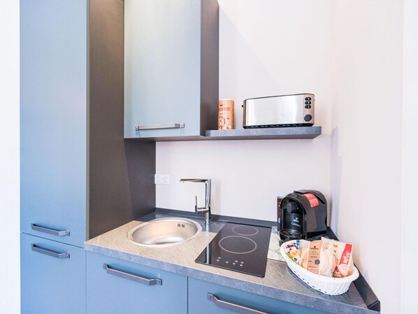 A modern kitchenette with a built-in stove, a sink, and a coffee maker. - Apartment Bad Camberg (Bad Camberg)