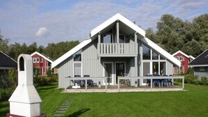 A modern two-story house with a large porch, a chimney, and a well-maintained lawn. - Exklusives Skandinavisches Ferienhaus for 6 (Rechlin)