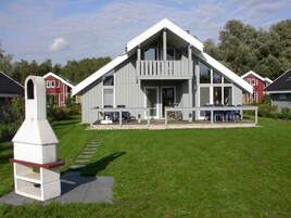 A modern two-story house with a large porch, a chimney, and a well-maintained lawn.