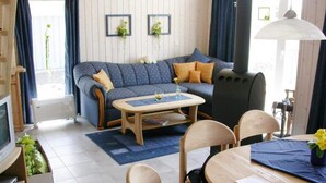A cozy living room with a sofa, coffee table, and chairs, a television, and a radiator. - Exklusives Skandinavisches Ferienhaus for 6 (Rechlin)