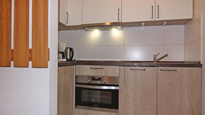 Eine kleine Küche mit Holzausstattung, einem Einbauofen und einer Kaffeemaschine.