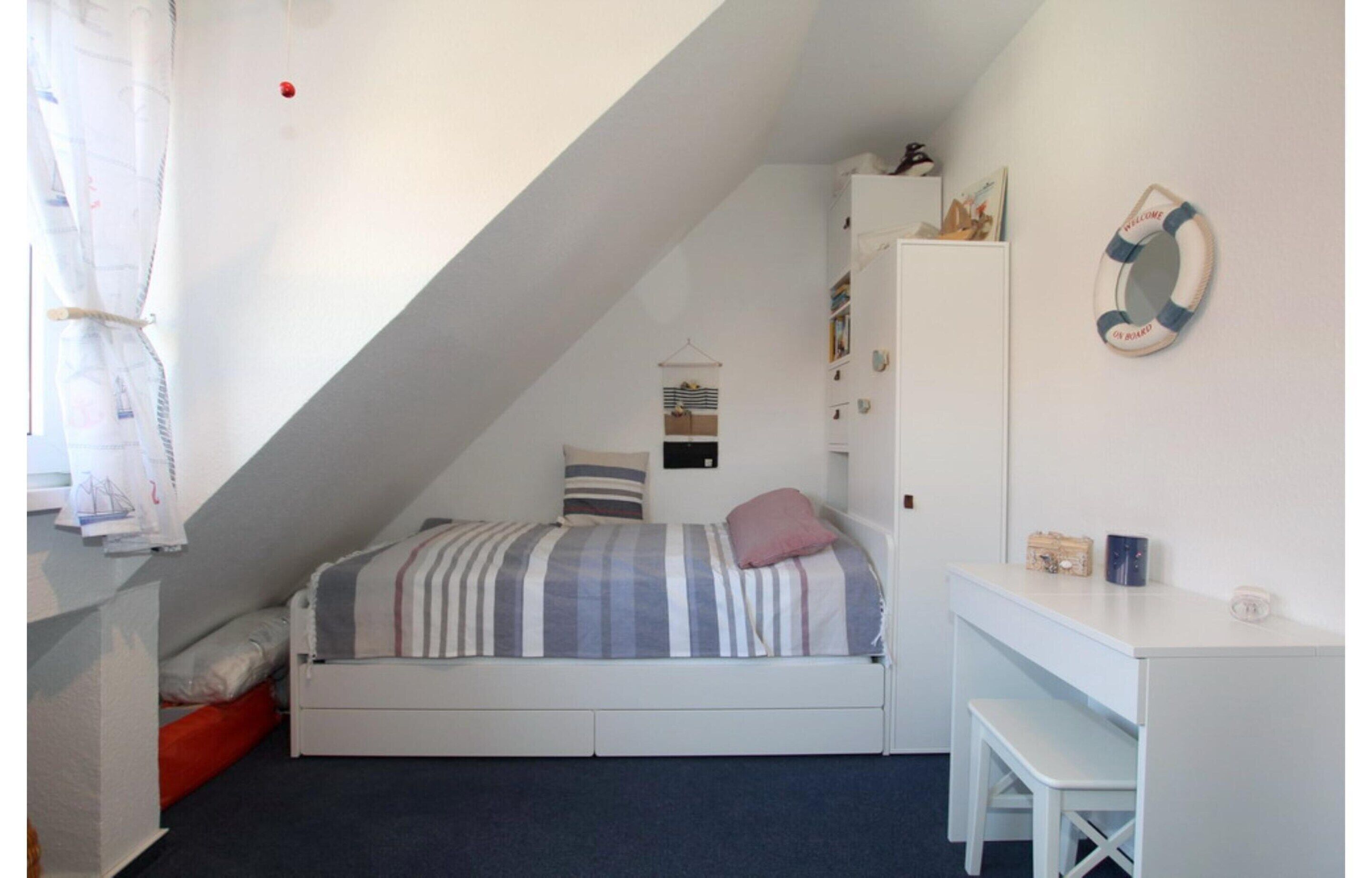 A small, cozy bedroom with a bunk bed, a desk, and a wardrobe.