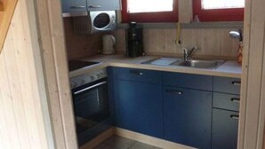 A compact kitchen with a built-in oven, a sink, and blue cabinets. - Skandinavisches Ferienhaus in Mirow (Mirow)