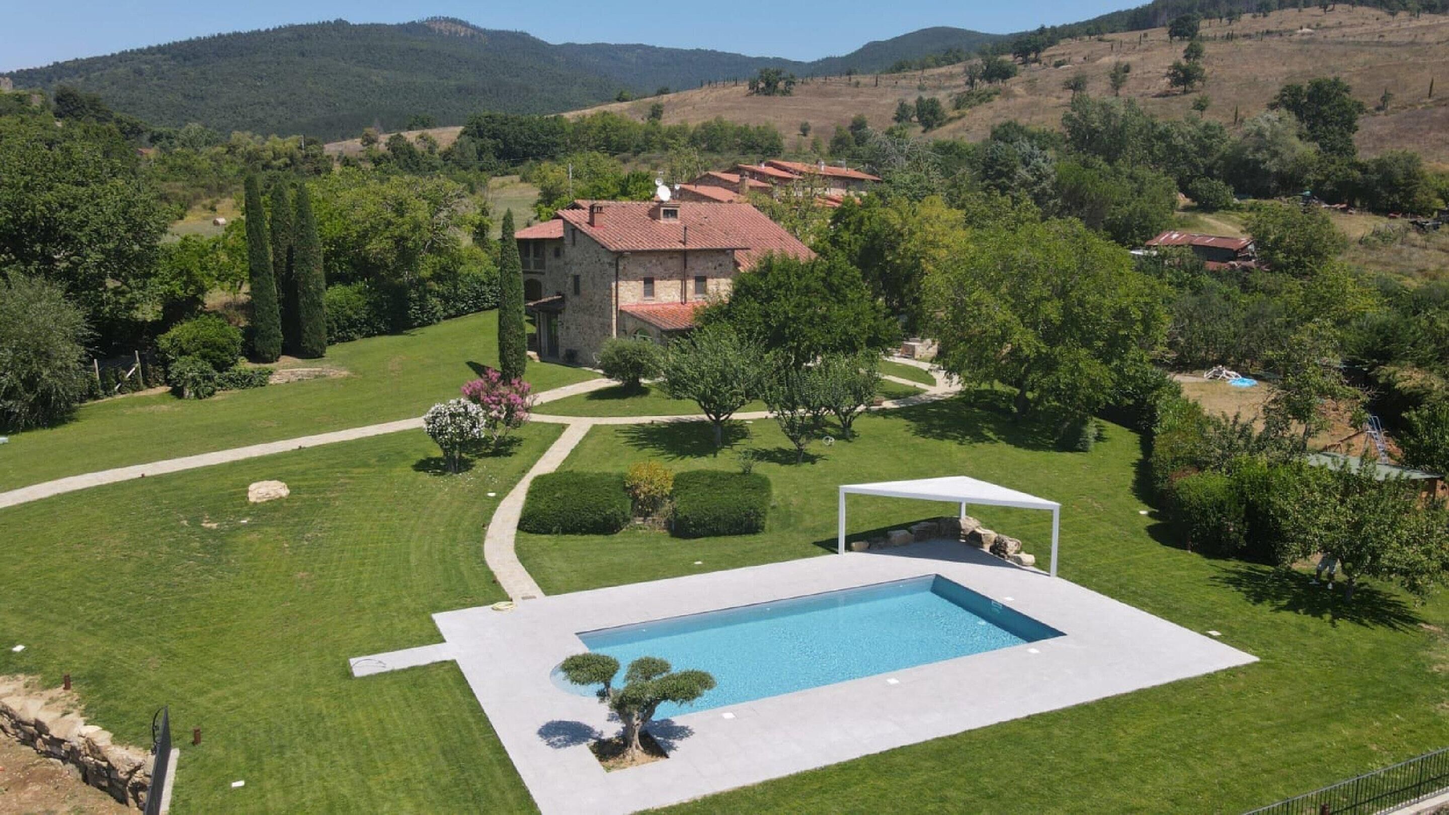 A house with a swimming pool, surrounded by a well-maintained lawn and trees.