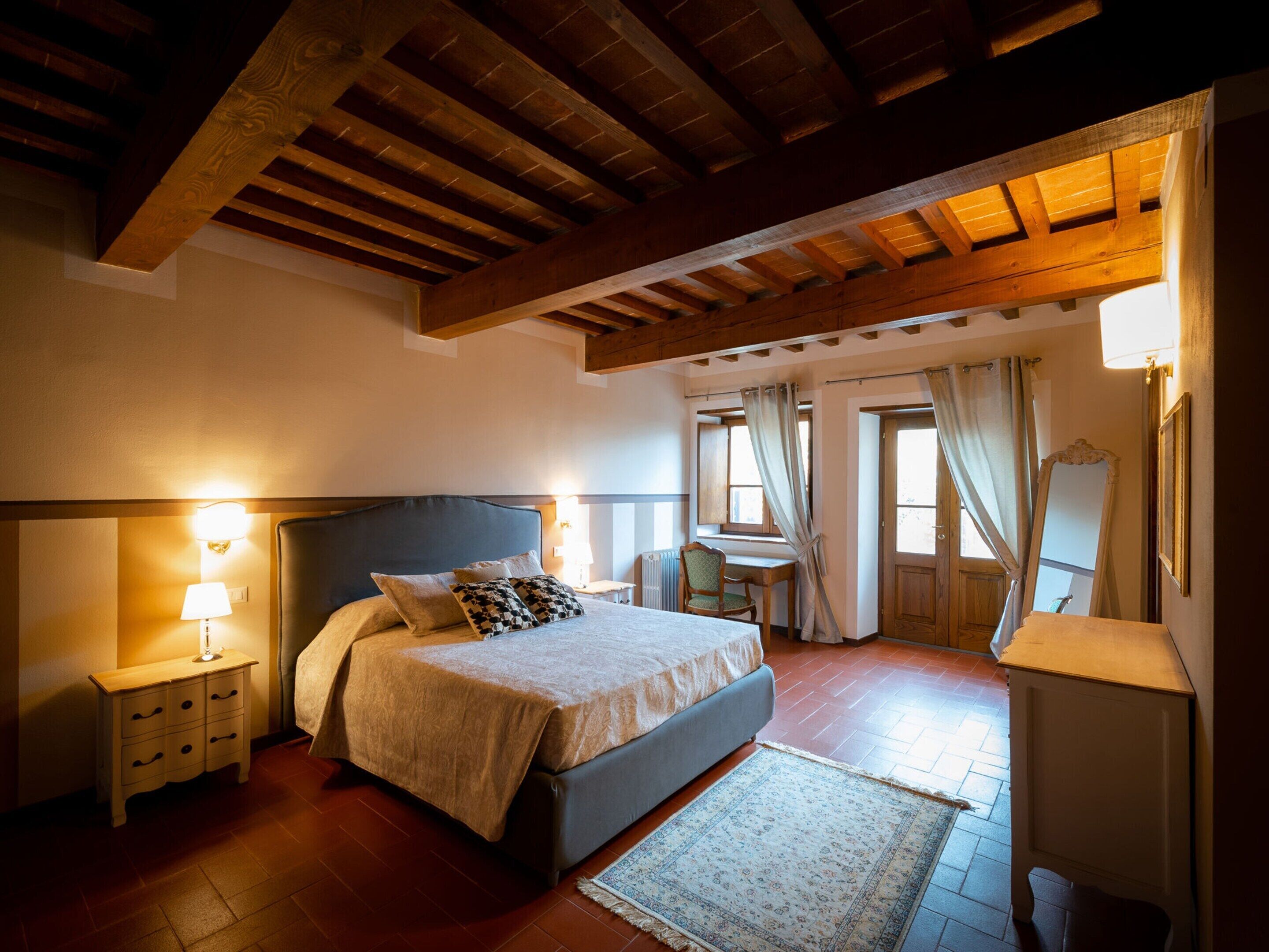 Un dormitorio con cama, mesitas de noche, un escritorio y una silla.
