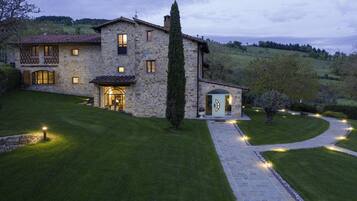 Una casa de piedra con un camino de entrada pavimentado y luces que iluminan el sendero.
