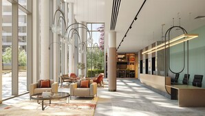 Eine großzügige Lobby mit einer Rezeption, einer Sitzecke und großen Fenstern mit Blick ins Freie.