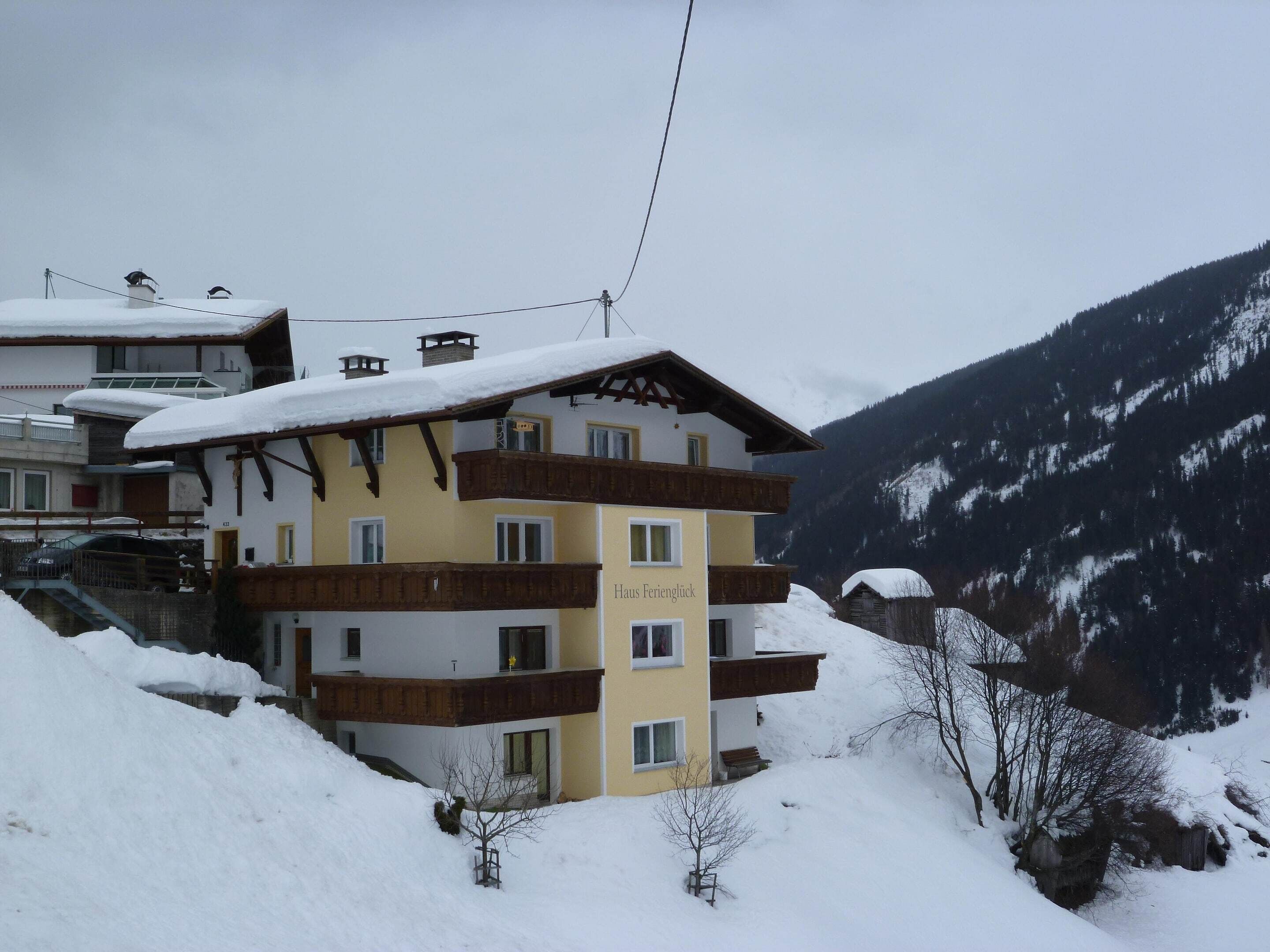 Ein mehrstöckiges Hotel mit Balkonen vor einer verschneiten Bergkulisse.