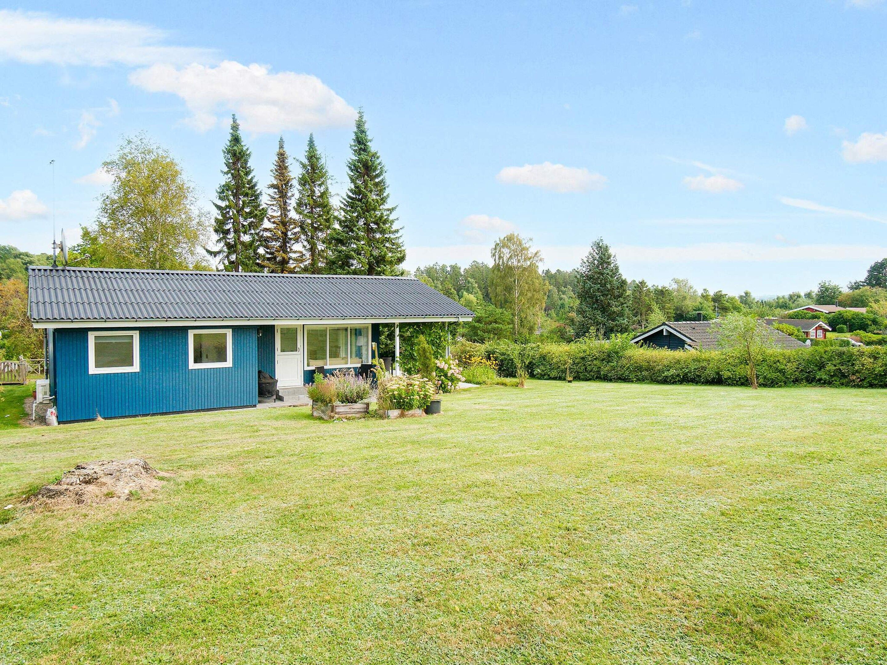 A blue house with a sloped roof, a front porch, and a well-maintained lawn.