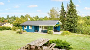 Une maison bleue avec un porche et une table de pique-nique dans la cour.