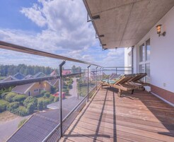 Una terraza de madera con barandilla de cristal que da a una zona residencial.