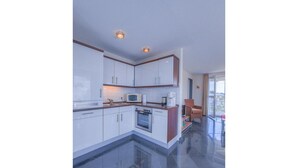 Une cuisine moderne avec des meubles blancs, un four à micro-ondes et une cuisinière.