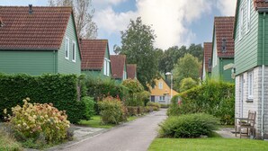 A residential street with houses on both sides, a paved road, and a grassy area with shrubs and flowers. - Zeeland Retreat; Sauna and Seaside Charm (Wemeldinge)