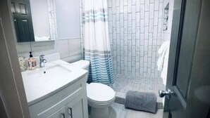 A modern bathroom with a shower, toilet, and sink. - 01 Coastal Cute 2 Bdrm - FLL-DT-Beach (Fort Lauderdale)