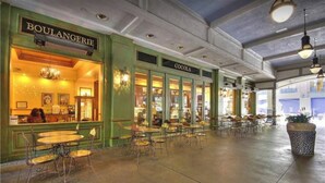 Un grand espace intérieur aménagé en salle à manger, avec de nombreuses tables et chaises, un mur végétal orné d’une enseigne indiquant « BOULANGERIE », et une autre enseigne pour « COCOA ».