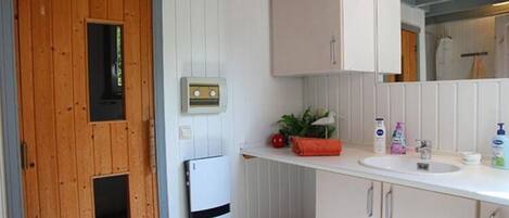 A compact kitchen with wooden cabinetry, a white countertop, and a built-in sink.