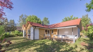 A two-story house with a red-tiled roof, a covered patio, and a small garden area. - Ferienhaus im Ferienpark Mirow (Mirow)
