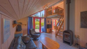 A cozy cabin interior with a living area, a wooden staircase, and a fireplace. - Ferienhaus im Ferienpark Mirow (Mirow)