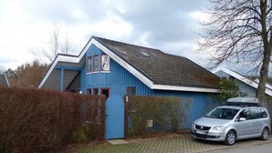Et blåt hus med en bil foran.