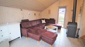 En hyggelig stue med en hjørnesofa, et sofabord og en pejs.