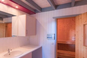 A bathroom with a white sink, a mirror, and wooden paneling.