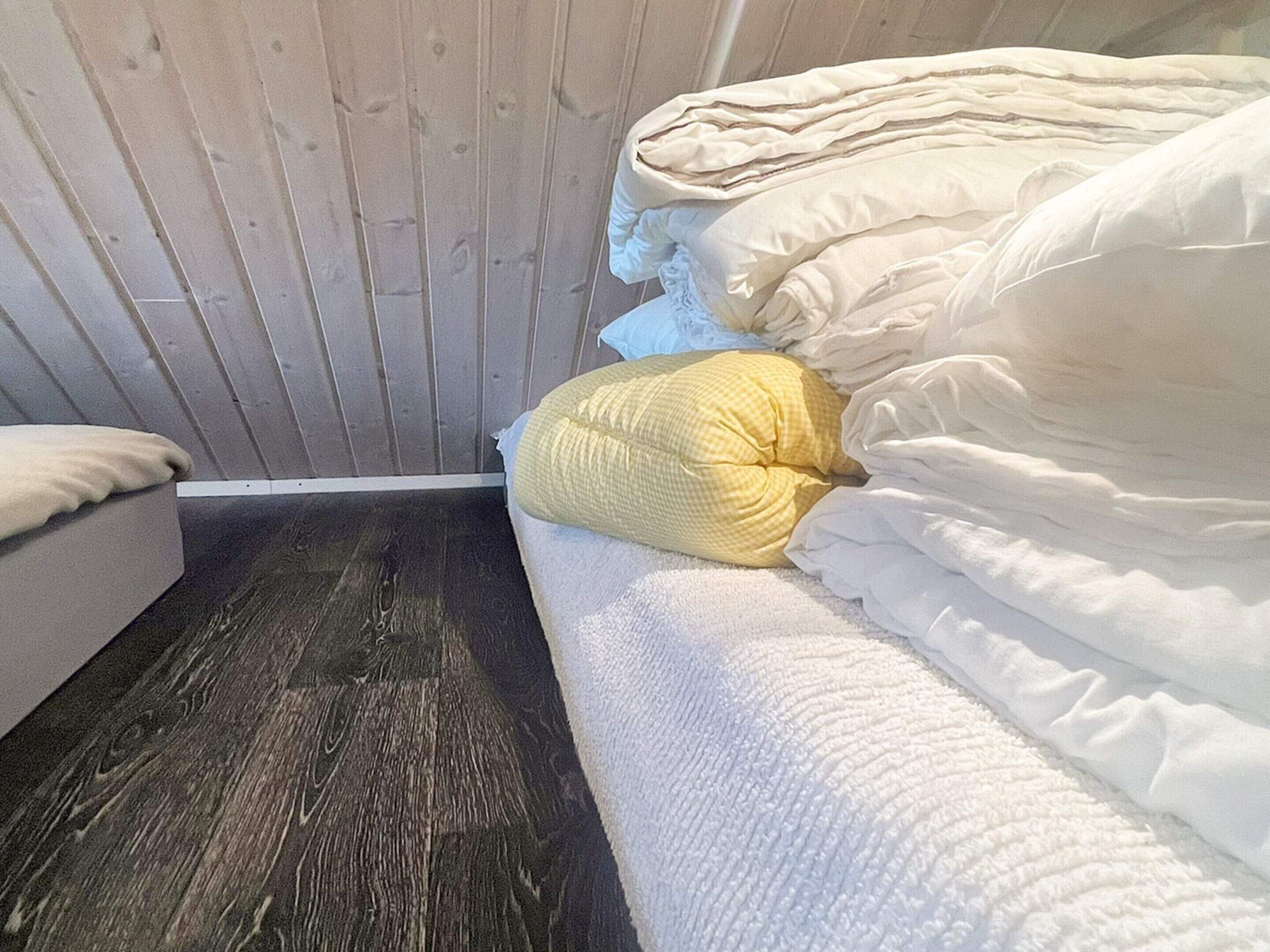 A room with a bed, a wooden wall, and a dark wooden floor.