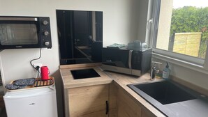 Een compacte keuken met een ingebouwde magnetron, een Samsung magnetron, een spoelbak en een kleine koelkast.
