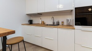 A modern kitchen with white cabinets, a wooden countertop, a stainless steel sink, and a built-in oven.