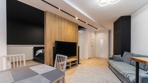 A modern living room with a TV, sofa, and dining area.