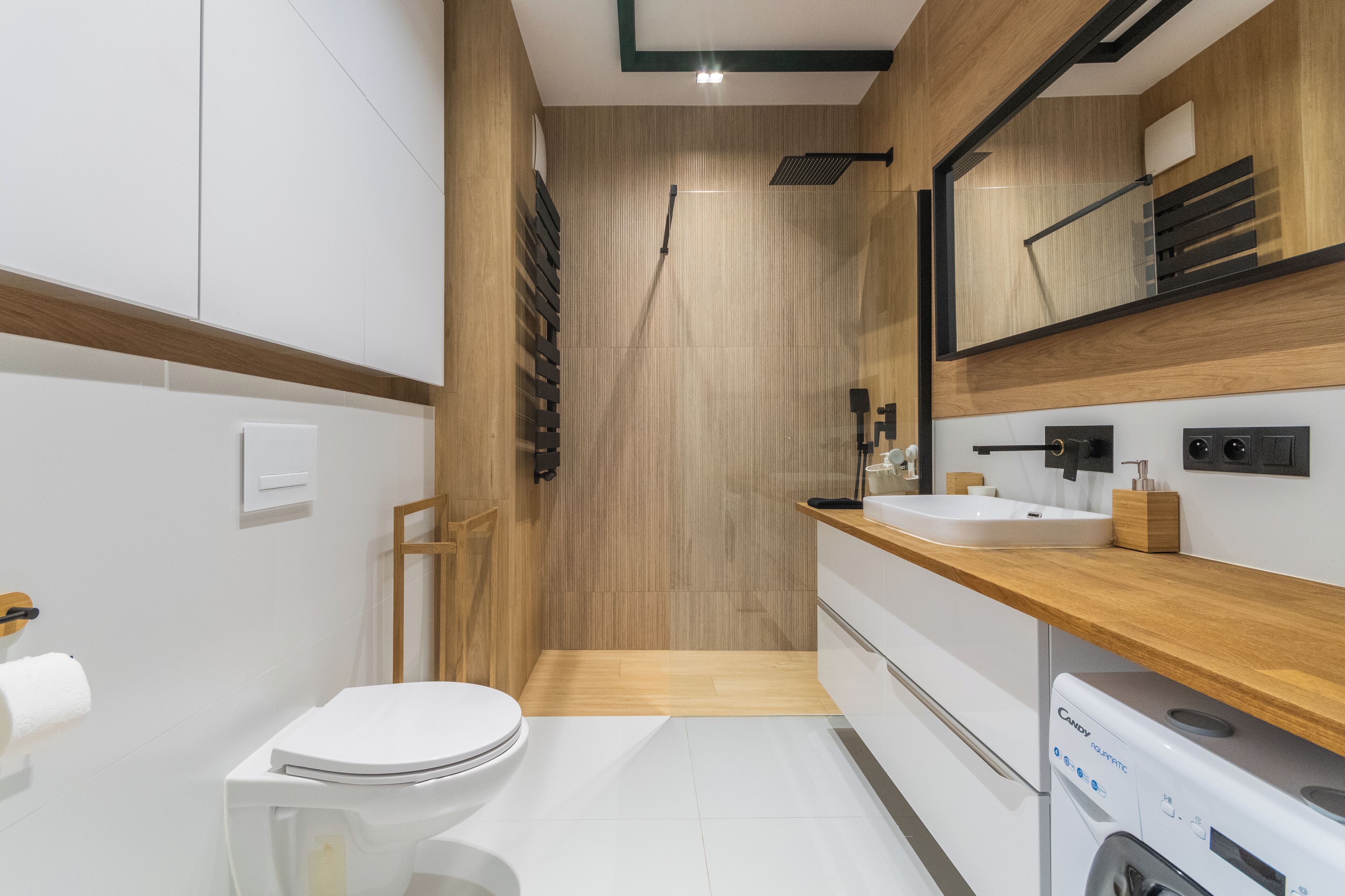 Ein modernes Badezimmer mit einem Holzkosmetikschrank, einem Waschbecken, einer Toilette und einer Waschmaschine.